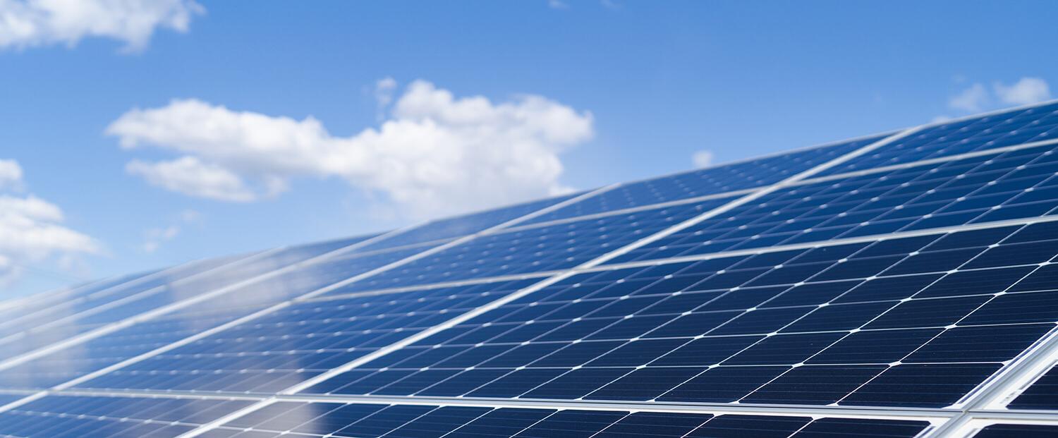 Angled solar panels against a blue sky with clouds